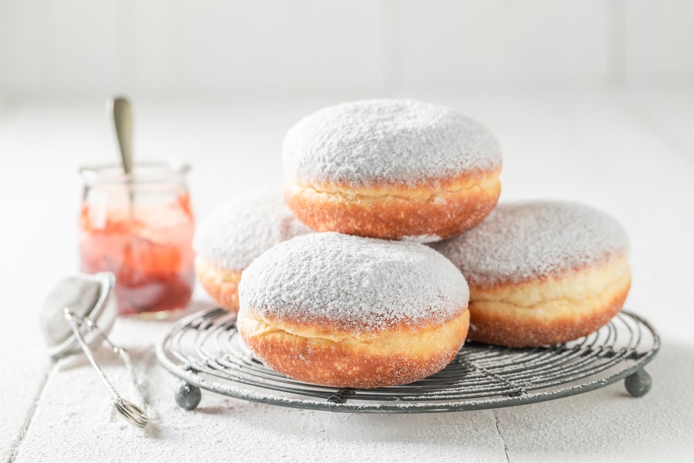 Donuts with powdered sugar on white table.