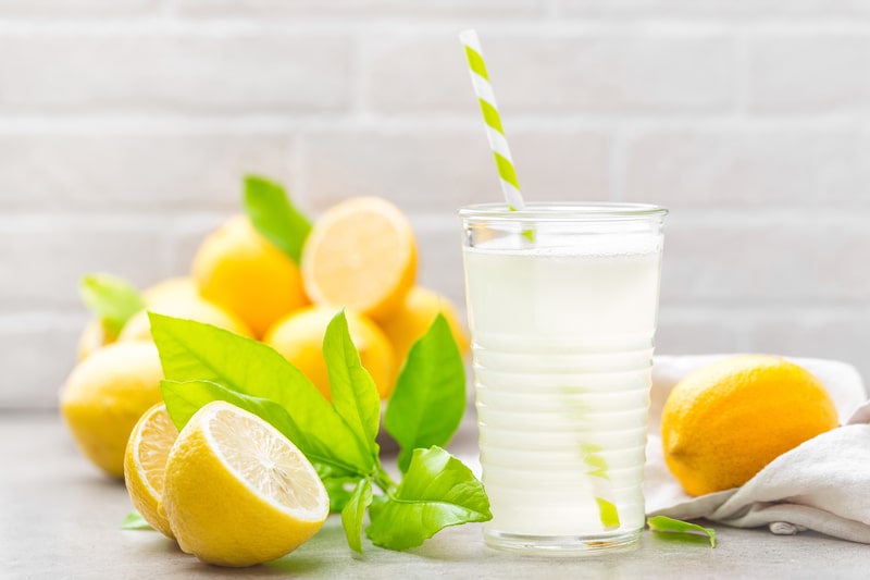 Lemonade drink with fresh lemons on the table.